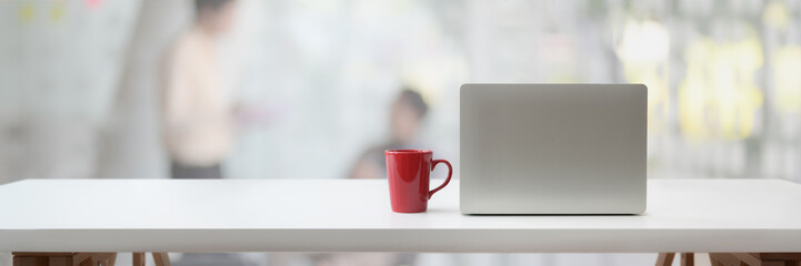 Cropped shot of workspace with laptop, coffee cup and copy space on white table