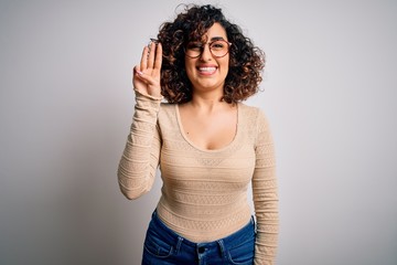 Young beautiful curly arab woman wearing casual t-shirt and glasses over white background showing and pointing up with fingers number three while smiling confident and happy.