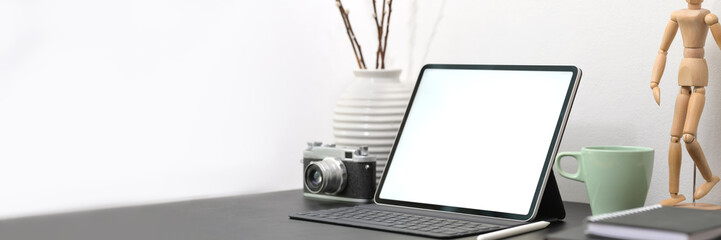 Cropped shot of minimal designer workspace with mock-up tablet, camera, supplies and decorations