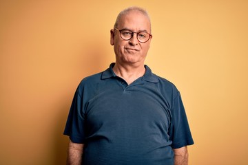 Middle age handsome hoary man wearing casual polo and glasses over yellow background looking sleepy and tired, exhausted for fatigue and hangover, lazy eyes in the morning.