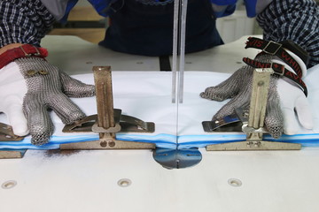 COVID-19 global outbreak. Workers on a surgical mask production line use metal cutters to cut the raw material for masks. Accelerate production of Personal Protective Equipment.