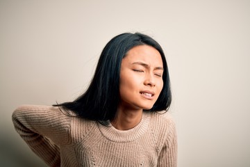 Young beautiful chinese woman wearing casual sweater over isolated white background Suffering of backache, touching back with hand, muscular pain