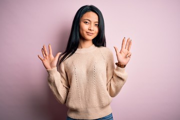 Young beautiful chinese woman wearing casual sweater over isolated pink background showing and...