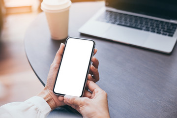 Mockup image blank white screen cell phone.woman hand holding texting using mobile on desk at coffee shop.background empty space for advertise text.people contact marketing business,technology