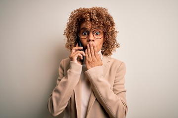 Young african american woman with curly having conversation talking on the smartphone cover mouth with hand shocked with shame for mistake, expression of fear, scared in silence, secret concept