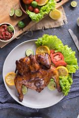 Flat lay top view of ayam penyet, a tradisional cuisine commonly found in Indonesia and Malaysia. Consist of spicy sauce, vegetable and roasted chicken whole or part.