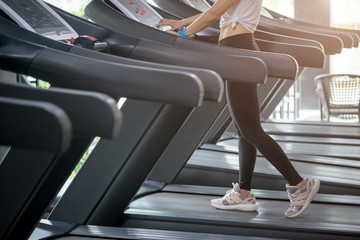 Fototapeta na wymiar Young woman at the gym exercising. Run on on a machine.