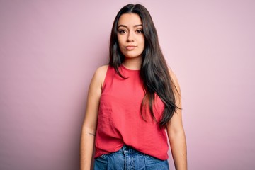 Obraz premium Young brunette woman wearing casual summer shirt over pink isolated background Relaxed with serious expression on face. Simple and natural looking at the camera.
