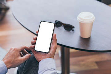 Mockup image blank white screen cell phone.man hand holding texting using mobile on desk at coffee shop.background empty space for advertise text.people contact marketing business,technology