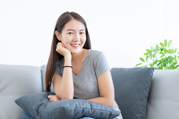 Attractive Asian young woman happy and relaxing portrait and sitting on gray color sofa decoration by plants tree in living room on white background