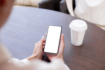 Mockup image blank white screen cell phone.woman hand holding texting using mobile on desk at coffee shop.background empty space for advertise text.people contact marketing business,technology