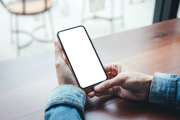 Mockup image blank white screen cell phone.woman hand holding texting using mobile on desk at coffee shop.background empty space for advertise text.people contact marketing business,technology