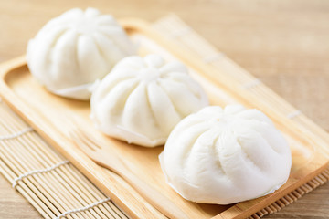 Fototapeta na wymiar Steamed buns stuffed with minced pork on wooden plate and fork ready to eating, Asian food