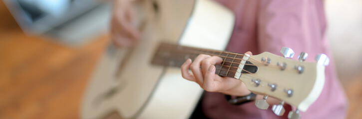 Close up view of young female music college student playing guitar - obrazy, fototapety, plakaty