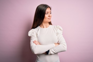 Obraz premium Young beautiful woman with blue eyes wearing casual white t-shirt over pink background looking to the side with arms crossed convinced and confident