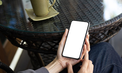 cell phone Mockup image blank white screen.woman hand holding texting using mobile on desk at coffee shop.background empty space for advertise text.people contact marketing business,technology