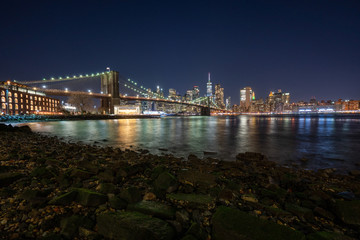 Panoramic Cityscape View of New York City at night with illuminated skyscrapers and bridges inside urban city center