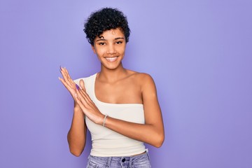 Young beautiful african american afro woman wearing casual t-shirt over purple background clapping and applauding happy and joyful, smiling proud hands together