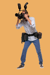 Full portrait of male journalist working with digital professional camera on orange skin color background