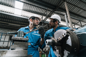 Engineer men wearing uniform safety in factory working machine lathe metal.