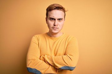 Young handsome redhead man wearing casual sweater over isolated yellow background skeptic and...