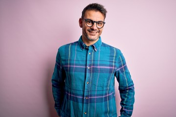 Young handsome man wearing casual shirt and glasses standing over isolated pink background with a happy and cool smile on face. Lucky person.