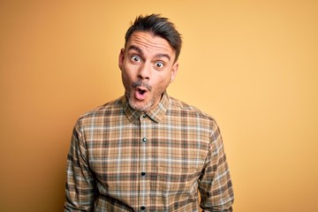 Obraz premium Young handsome man wearing casual shirt standing over isolated yellow background afraid and shocked with surprise expression, fear and excited face.