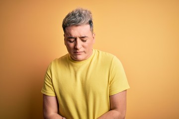 Obraz premium Young handsome modern man wearing yellow shirt over yellow isolated background with hand on stomach because indigestion, painful illness feeling unwell. Ache concept.