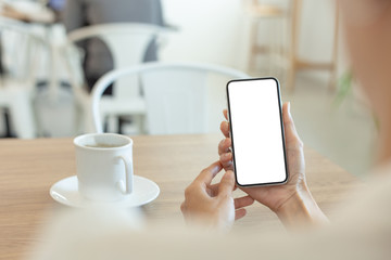 cell phone Mockup image blank white screen.woman hand holding texting using mobile on desk at coffee shop.background empty space for advertise text.people contact marketing business,technology