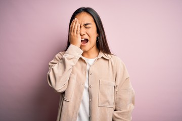 Young beautiful asian woman wearing casual shirt standing over pink background Yawning tired covering half face, eye and mouth with hand. Face hurts in pain.