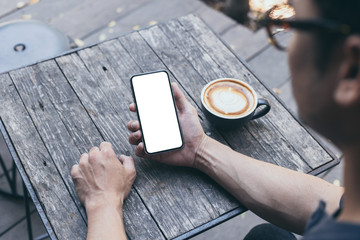 cell phone Mockup image blank white screen.man hand holding texting using mobile on desk at coffee shop.background empty space for advertise text.people contact marketing business,technology