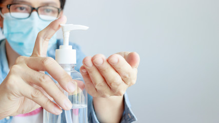 a man wearing medical protective mask and using sanitizer gel on his hands as prevention measures against coronavirus COVID-19