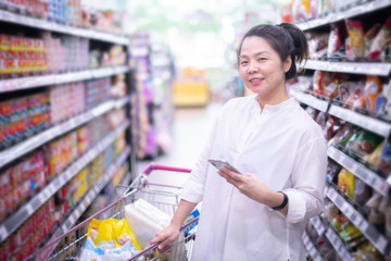 Asian beautiful woman using smart phone shopping in super market