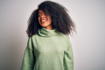 Young beautiful african american woman with afro hair wearing green winter sweater looking away to side with smile on face, natural expression. Laughing confident.