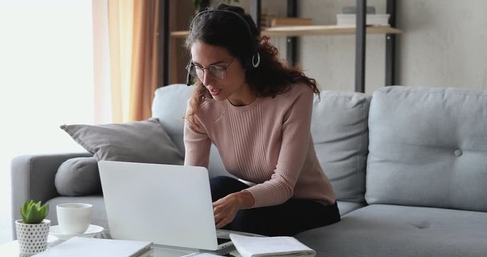 Millennial woman wearing headset making video chat working from home using laptop. Young female online teacher conferencing on business call communicating by webcam on computer. Distance telework.