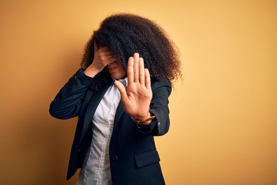 Young beautiful african american business woman with afro hair wearing elegant jacket covering eyes with hands and doing stop gesture with sad and fear expression. Embarrassed and negative concept.