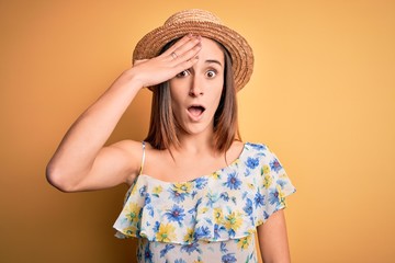 Young beautiful woman wearing casual t-shirt and summer hat over isolated yellow background...