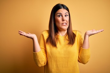 Young beautiful woman wearing casual sweater over yellow isolated background clueless and confused...