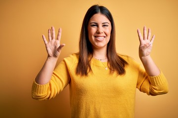 Young beautiful woman wearing casual sweater over yellow isolated background showing and pointing...
