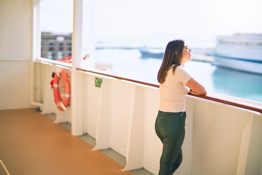 Young beautiful woman on vacation smiling happy and confident. Standing on a deck of ship with smile on face doing a cruise