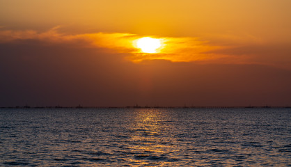Obraz premium Colorful sunrise at sea, oil platforms in distance