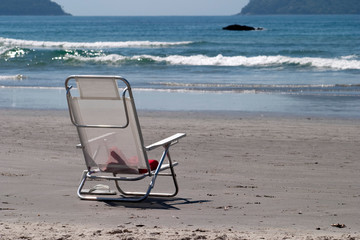 Fototapeta na wymiar White beach chair abandoned in the sand