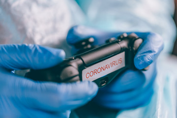 Man in a protective medical suit and gloves with a gamepad. video games and gaming during quarantine, self-isolation. COVID-19 pandemic coronavirus. stay home