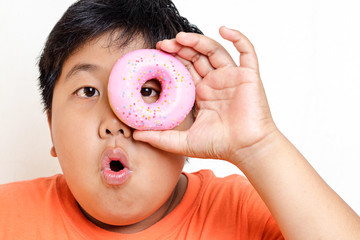 Asian fat boy holds a strawberry-coated donut He enjoys eating. Food concepts that cause children's...