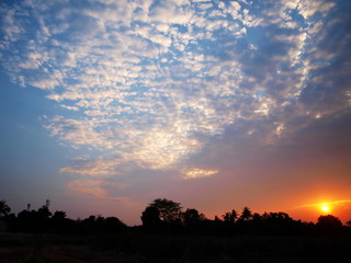 Fototapeta premium Reflections of clouds white sunset and silhouette of trees below the mountain. Selective focus.