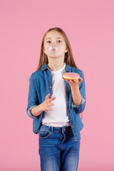 Little girl with sun glasses blowing up pink chewing gum against a light purple background