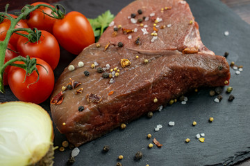A marinated piece of fresh meat with tomato and onion seasoning is ready to cook.