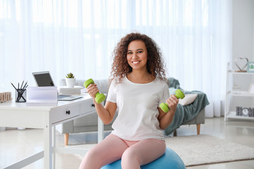 Young woman doing exercises with fitness ball at home
