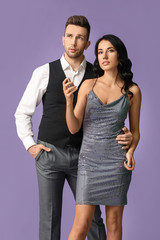 Stylish young couple with perfume on color background