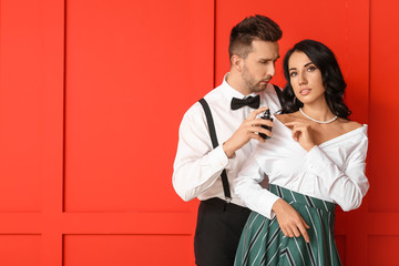 Stylish young couple with perfume on color background